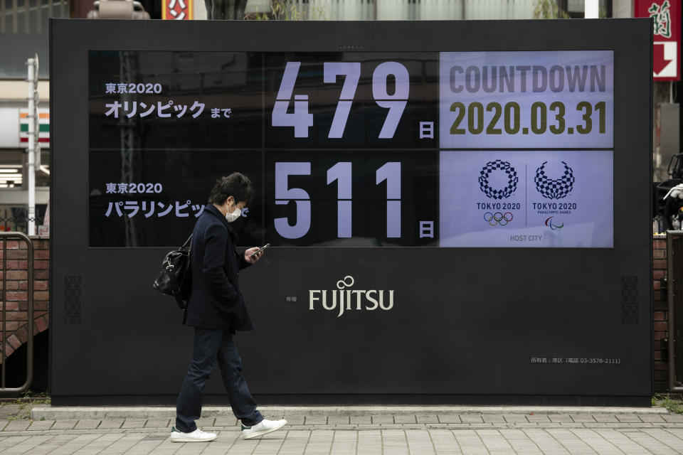 FILE - In this March 31, 2020, file photo, a man walks past a countdown display for the Tokyo 2020 Olympics and Paralympics in Tokyo. The countdown clock is ticking again for the Tokyo Olympics. They will be July 23 to Aug. 8, 2021. The clock read 479 days to go. (AP Photo/Jae C. Hong, File)