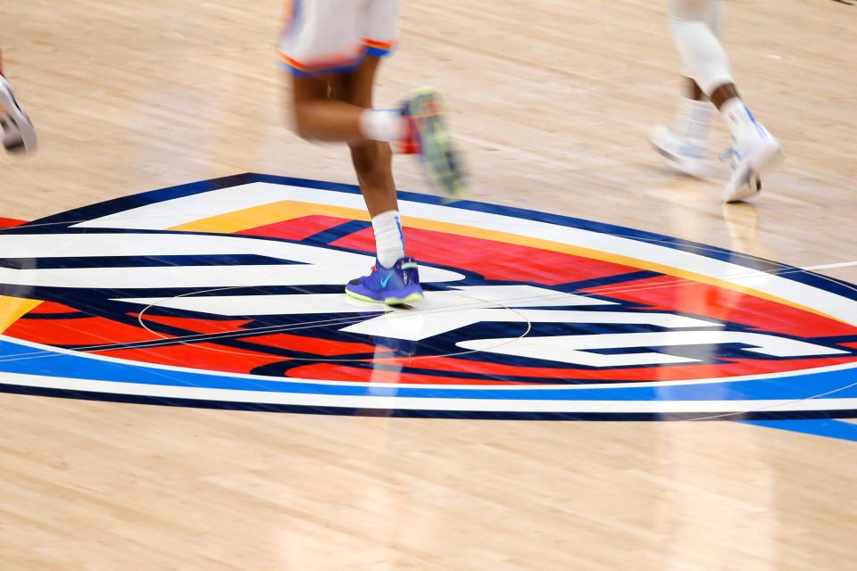 Players runs past the OKC Thunder's midcourt during an NBA basketball game.