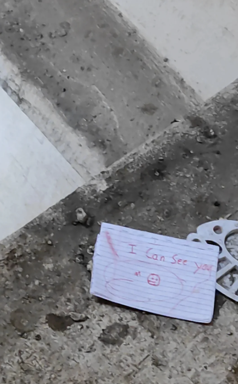 Handwritten note on ground with text "I can see you" and a smiley face