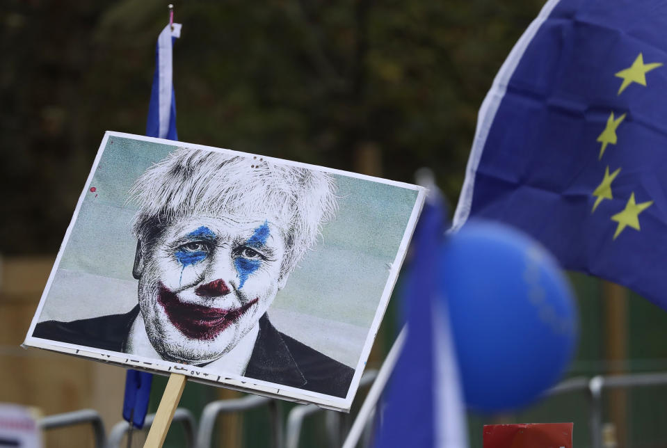 Opositores al Brexit sostienen una pancarta con la cara del primer ministro británico Boris Johnson pintada como el Guasón mientras participan en una protesta para exigir otro referendo sobre la membresía de Gran Bretaña en la Unión Europea en Londres, el sábado 19 de octubre de 2019. (AP Foto/Matt Dunham)