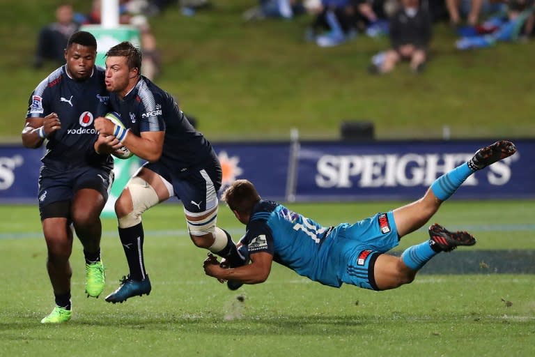 Handre Pollard of the Northern Bulls (C) breaks a tackle by Piers Francis of the Auckland Blues (R) during their Super Rugby match in Auckland