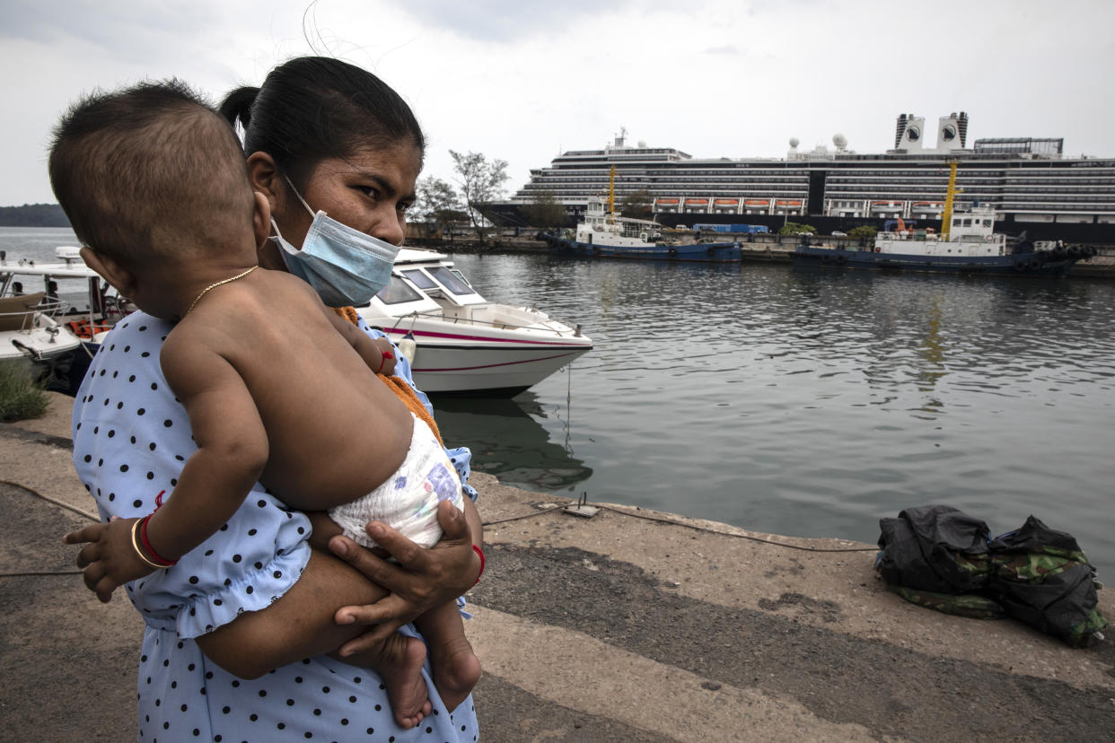 SIHANOUKVILLE - FEBRUARY 17 : A Cambodian woman wears a mask holding her baby on the dock outside the MS Westerdam cruise ship docked in Sihanoukville, Cambodia on February 17, 2020. There are currently 233 passengers and 747 crew members on board who were tested again. As the ship was declared free of the Coronavirus (COVID-19  ) over 1,000 passengers took charter flights to Phnom Penh, one elderly American woman was later found to be infected while transiting in Malaysia. The cruise ship departed Hong Kong February 1st with 1,455 passengers and 802 crew on board. (Photo by Paula Bronstein/Getty Images )