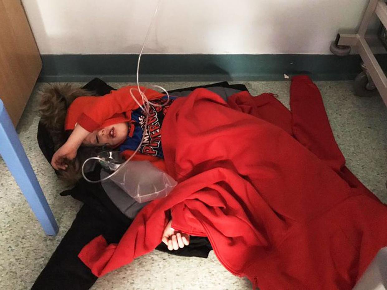 Four-year-old Jack Williment covered in coats on the floor with tubes coming out of him at Leeds General Infirmary because of a lack of beds: Mirrorpix