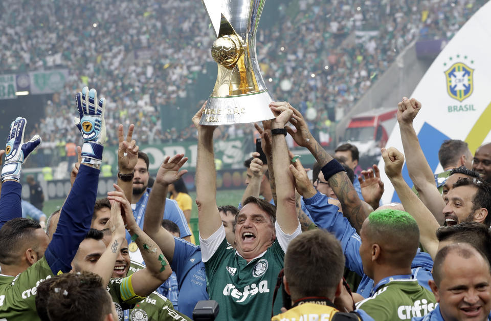 Brazil's President-elect Jair Bolsonaro holds up the national league soccer championship trophy as he celebrates with the Palmeiras soccer club in Sao Paulo, Brazil, on Sunday, Dec. 2, 2018. Bolsonaro handed the trophy to Palmeiras after the team's 3-2 home win against Vitoria. (AP Photo/Andre Penner)