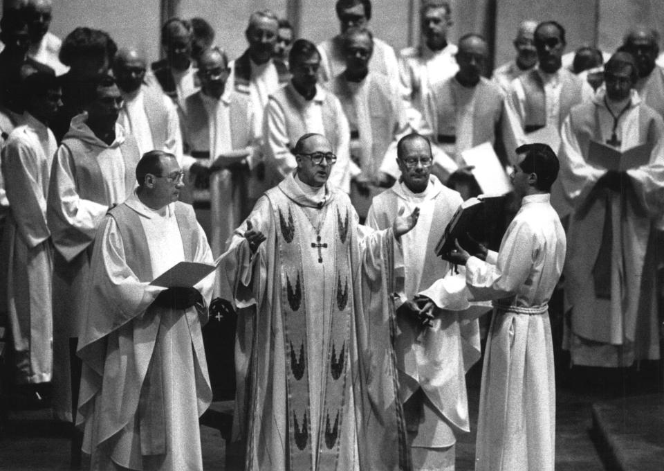 Father Albert J. DiUlio, left, looks on as Archbishop Rembert Weakland celebrates DiUlio's inaugural Mass as Marquette University  president in 1990. At right is Father Bert Thelen, head of the Wisconsin Province of the Society of Jesus. More than 90 priests also took part in the Mass.