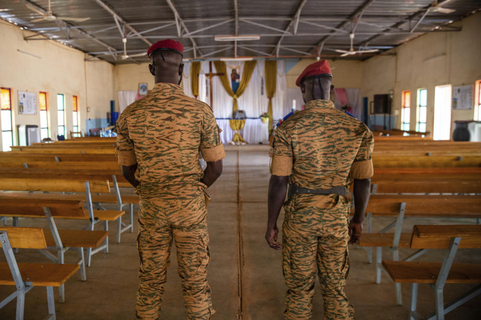 Two soldiers stand in the Catholic church at the 10th RCAS army barracks in Kaya, Burkina Faso, Saturday, April 10, 2021. Once considered a beacon of peace and religious coexistence in the region, the West African nation has been embroiled in unprecedented violence linked to al-Qaida and the Islamic State since 2016, throwing an ill-equipped and undertrained army into disarray — and overwhelming the chaplains tasked with supporting them. (AP Photo/Sophie Garcia)