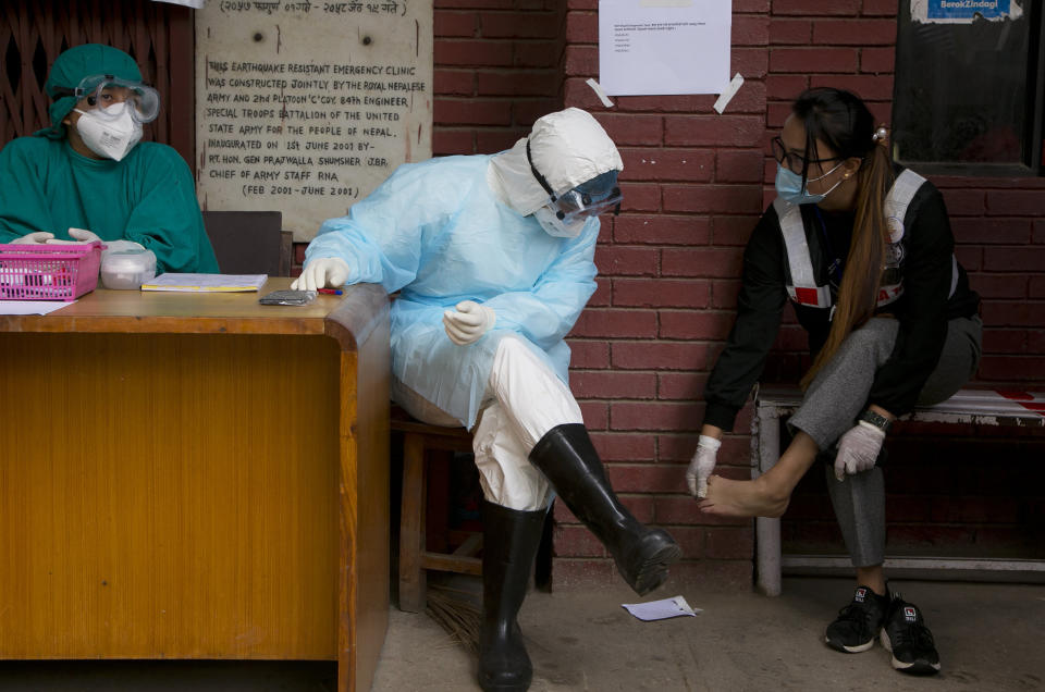 Punam Karmacharya, 22, of the RNA-16 volunteer group, consults with a doctor about the pain on her feet at a hospital in Bhaktapur, Nepal. Tuesday, May 26, 2020. RNA-16 stands for “Rescue and Awareness” and the 16 kinds of disasters they have prepared to deal with, from Nepal’s devastating 2015 earthquake to road accidents. But the unique services of this group of three men and a woman in signature blue vests in the epidemic amount to a much greater sacrifice, said doctors, hospital officials and civic leaders. (AP Photo/Niranjan Shrestha)