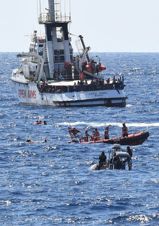 Migrants jump off the Spanish rescue ship Open Arms, close to the Italian shore in Lampedusa