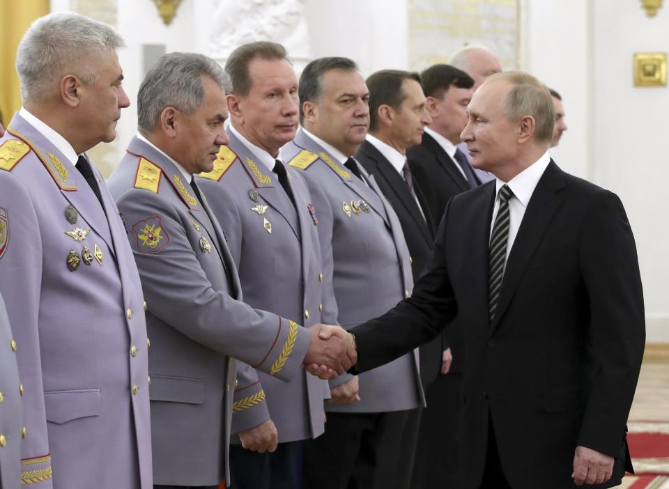 Russian President Vladimir Putin shakes hands with Defense Minister Sergei Shoigu, second left, as he greets senior military officers during a meeting in Moscow, Russia, Wednesday, Nov. 6, 2019. Putin said Russia's new weapons have no foreign equivalents but he insists the country will not use them to threaten anyone. (Mikhail Klimentyev, Sputnik, Kremlin Pool Photo via AP)