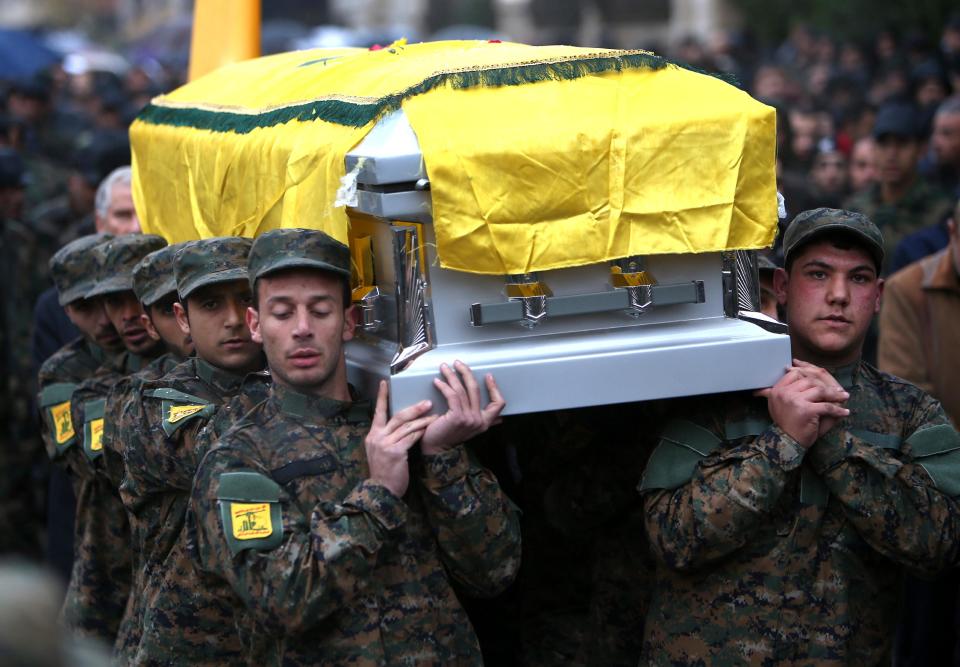 In this December 4, 2013 photo, Hezbollah fighters carry the coffin of Hassan al-Laqis, a senior commander for the Lebanese militant group Hezbollah who was gunned down outside his home, during his funeral procession, at his hometown in Baalbek city, east Lebanon. The Shiite group has sent hundreds of its fighters into Syria to shore up President Bashar Assad’s overstretched troops, helping them gain ground around the capital, Damascus, and near the Lebanese border. But with its own casualties mounting in a civil war that activists say has killed more than 150,000 people in three years, officials say Hezbollah has turned to a variety of new tactics - including complicated commando operations - to hunt down rebels and opposition commanders. (AP Photo/Hussein Malla)