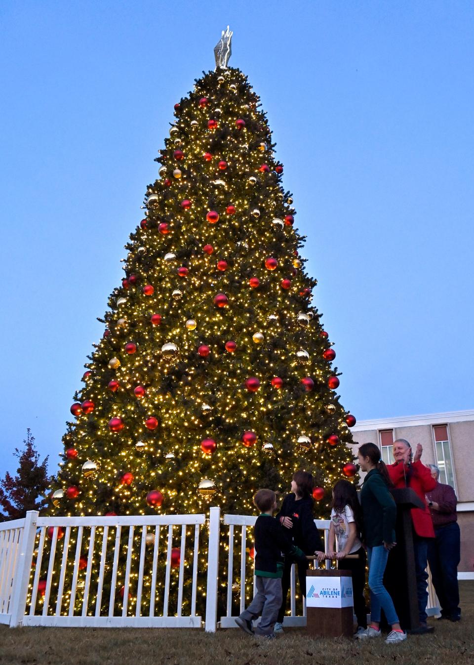Abilene Mayor Weldon Hurt claps as children light the city’s Christmas tree outside city hall Tuesday Nov. 28, 2023.