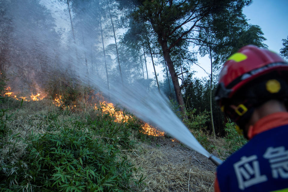 A firefighter puts out wildfire that broke out in a forest amid hot temperatures, in Luzhou, Sichuan province, China August 22, 2022. cnsphoto via REUTERS ATTENTION EDITORS - THIS IMAGE WAS PROVIDED BY A THIRD PARTY. CHINA OUT.