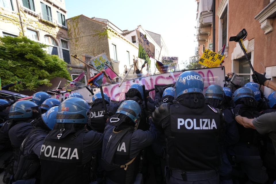 Demonstrators push their placards against a line of Italian Policemen in riot gears during a protest against the G20 Economy and Finance ministers and Central bank governors' meeting in Venice, Italy, Saturday, July 10, 2021. (AP Photo/Luca Bruno)