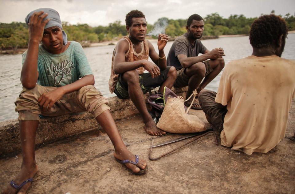 Workers sit on a dock as they wait to offload water storage containers destined for local villages on December 04, 2019 in Tanna, Vanuatu.