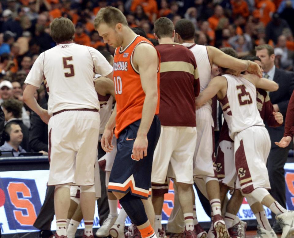 Syracuse's Trecor Cooney walks off the court as Boston College players celebrate after Boston College defeated Syracuse 62-59 in overtime in an NCAA college basketball game in Syracuse, N.Y., Wednesday, Feb. 19, 2014. (AP Photo/Kevin Rivoli)