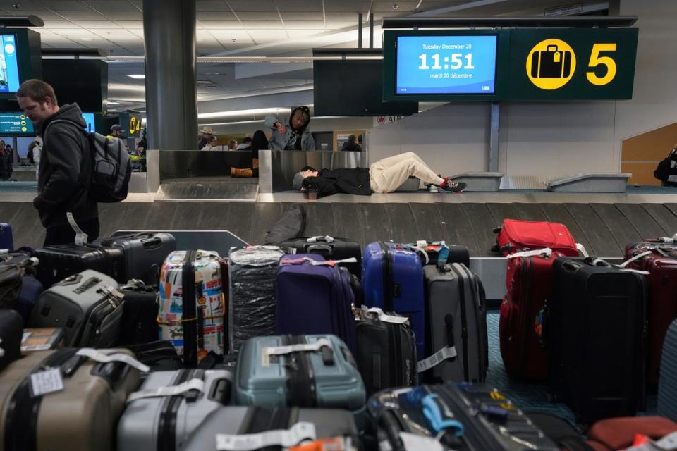 A man rests on a carousel as the cases mount up on at Vancover International Airport (AP)