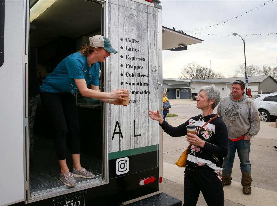 Kari Berg hands an iced latte to her mother-in-law, Kristi Sheetz of Keota, Iowa, as Jon Baker waits for his drink outside the Rural Revival mobile coffee truck spot in Keota, on Saturday, April 23, 2022.