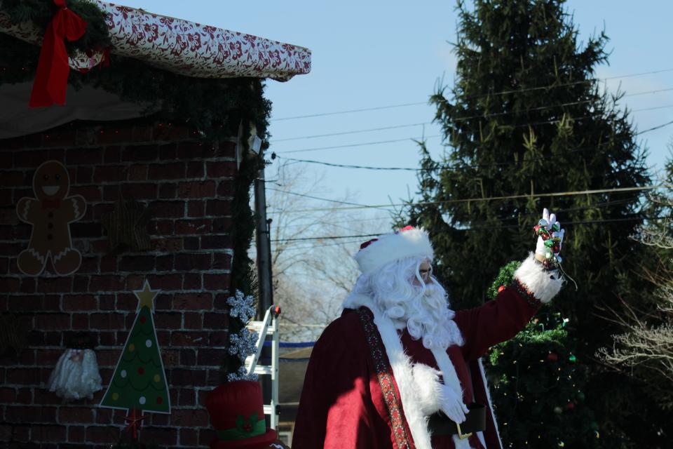 Trevor Webster waves at the passing cars from his yard wearing his custom tailored Santa suit as a way to let people know he is out there.