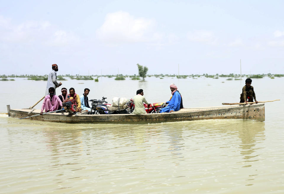 Pakistani men uses a boat to salvage usable items from their flood-hit homes in Dadu district of Sindh Province in southern Pakistan, Saturday, Aug. 27, 2022. Officials say flash floods triggered by heavy monsoon rains across much of Pakistan have killed nearly 1,000 people and displaced thousands more since mid-June. (AP Photo/Pervez Masih)