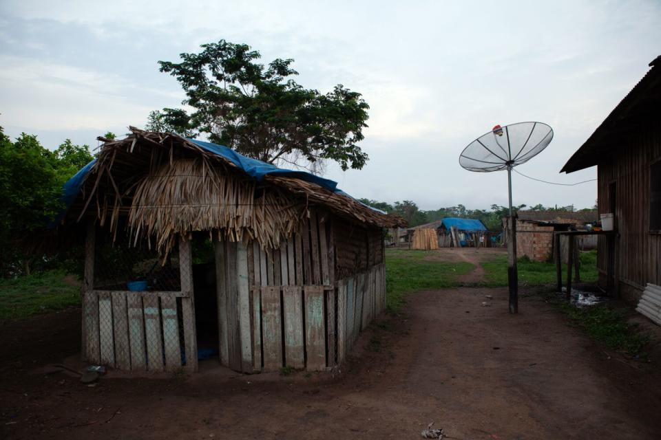 A hutlike home in a village with a large round antenna nearby