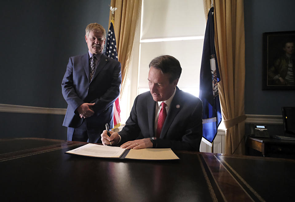 Gov. Glenn Youngkin, right, signs his administration's first bill, HB828, the Dairy Producer Margin Coverage Premium Assistance Program patroned by Del. Tony Wilt, R-Rockingham, left, inside the State Capitol in Richmond, Va., on Monday, Feb. 14, 2022. (Bob Brown/Richmond Times-Dispatch via AP)