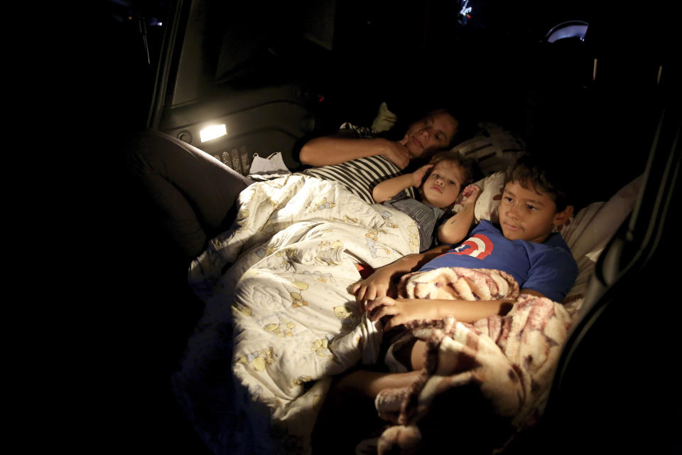 Ana Paula Santos y sus niños miran una película desde su auto en un autocine en Brasilia, 13 de mayo de 2020 (AP Foto/Eraldo Peres)