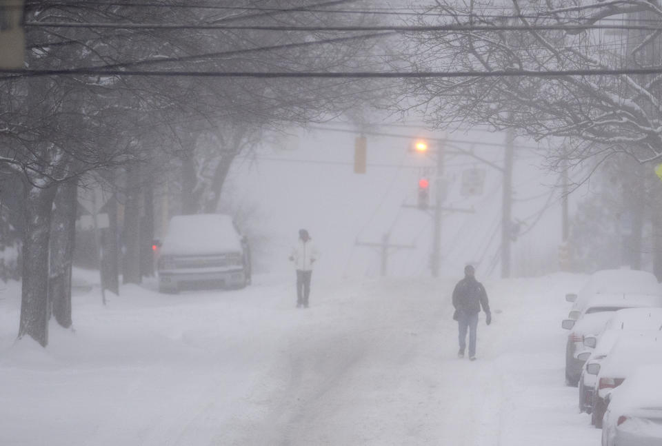 Pedestrians make their way down a partially plowed Murray Avenue Monday, Jan. 17, 2022, in Squirrel Hill neighborhood of Pittsburgh. (Pam Panchak/Pittsburgh Post-Gazette via AP)