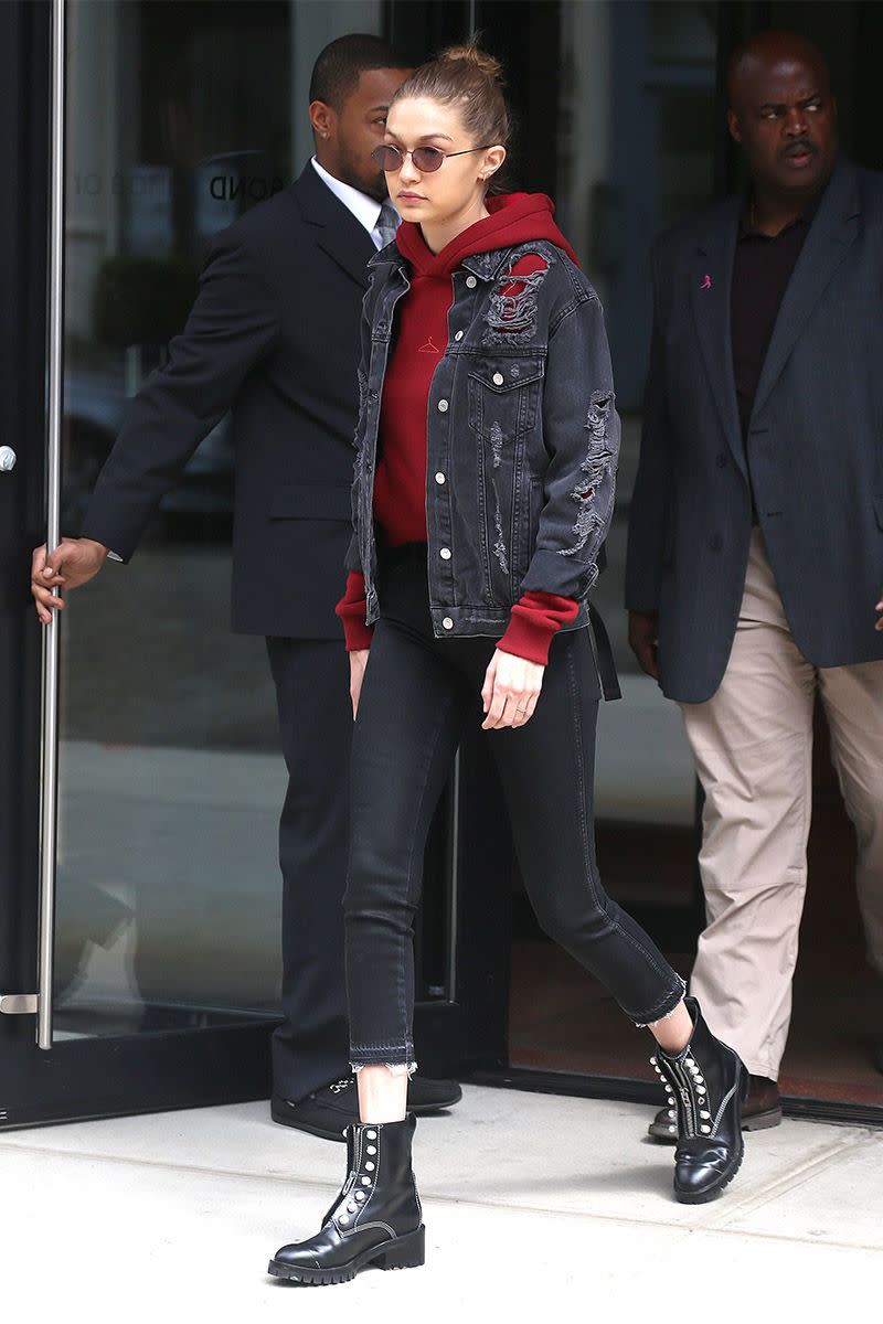 <p>In a blood red hoodie, distressed denim jacket, cropped black jeans, studded ankle combat boots and round sunglasses while out in New York City.</p>