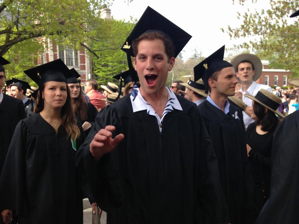 Evan Gershkovich poses for the camera with his mouth open wearing a graduation cap and gown.