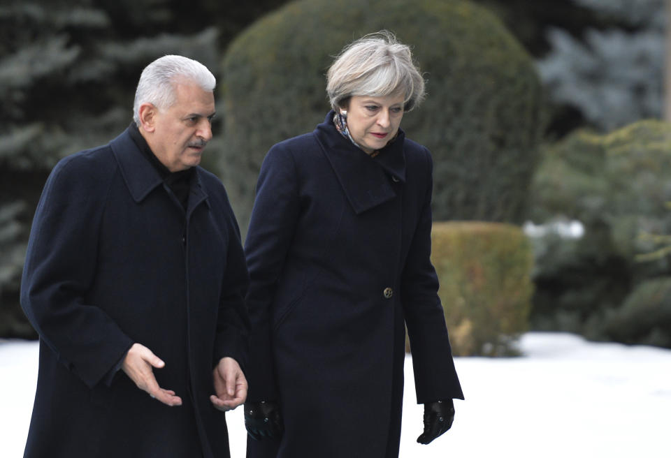 Turkey's Prime Minister Binali Yildirim, left, walks with British Prime Minister Theresa May, centre, during her welcome ceremony prior to their meeting in Ankara, Turkey, Saturday, Jan. 28, 2017. May on Saturday urged Turkey to sustain its democracy and abide by human rights standards during her meeting with Turkish President Recep Tayyip Erdogan that also drew promises of closer defense cooperation between the two NATO allies. (AP Photo)