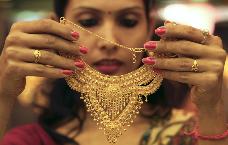 A salesgirl shows a gold necklace to customers at a jewellery showroom in the northern Indian city of Chandigarh November 11, 2012. Gold importers in India, the world's biggest buyer of bullion, paused on fresh purchases ahead of key festivals next week, as a weaker rupee helped the yellow metal hit its highest level in seven weeks. REUTERS/Ajay Verma (INDIA - Tags: BUSINESS COMMODITIES)