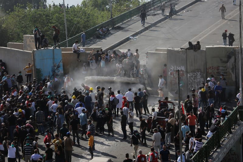 Iraqi demonstrators smash concrete walls at Sinak Bridge during the ongoing anti-government protests, in Baghdad