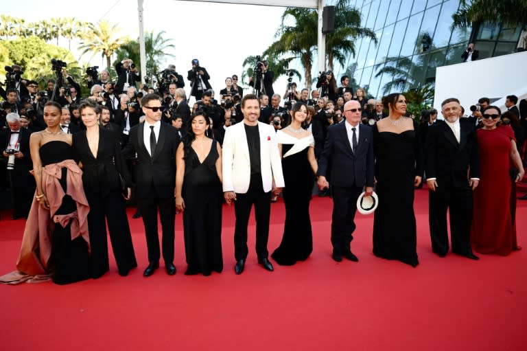 El director francés Jacques Audiard (centro, con gafas oscuras y un sombrero en la mano), con el reparto de la película "Emilia Pérez", en el Festival de Cine de Cannes, en Francia, el 18 de mayo de 2024 (Christophe Simon)