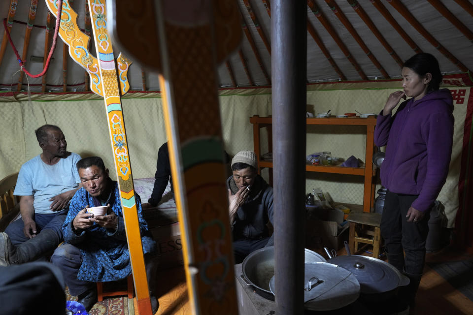 Lkhaebum, left, with his daughter-in-law, Nurmaa, right, and others shelter inside their ger during a sudden dust storm in the Munkh-Khaan region of the Sukhbaatar district, in southeast Mongolia, Saturday, May 13, 2023. The family has a solar-powered battery that runs a television and washing machine, a karaoke machine, and a cellphone to keep track of weather and access Facebook groups where herders exchange information. (AP Photo/Manish Swarup)