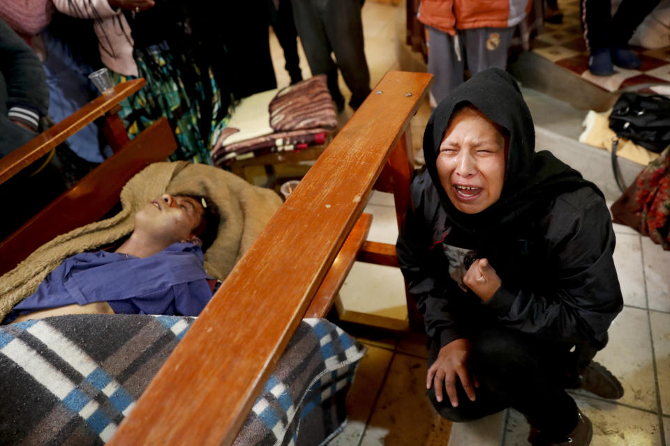 Gloria Quispe mourns next to the body of her brother Antonio, killed during clashes between security forces and supporters of former President Evo Morales, at the San Francisco de Asis church in El Alto, outskirts of La Paz, Bolivia, Nov. 20, 2019. Police and soldiers on Tuesday escorted gasoline tankers from a major fuel plant that had been blockaded for five days by Morales' backers and at least three people were reported killed while the operation was underway. (AP Photo/Natacha Pisarenko)