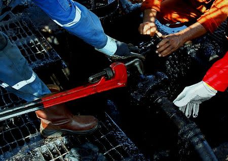 Men work at an oil pump in Lagunillas, Ciudad Ojeda, in the state of Zulia, Venezuela, March 20, 2015. REUTERS/Isaac Urrutia