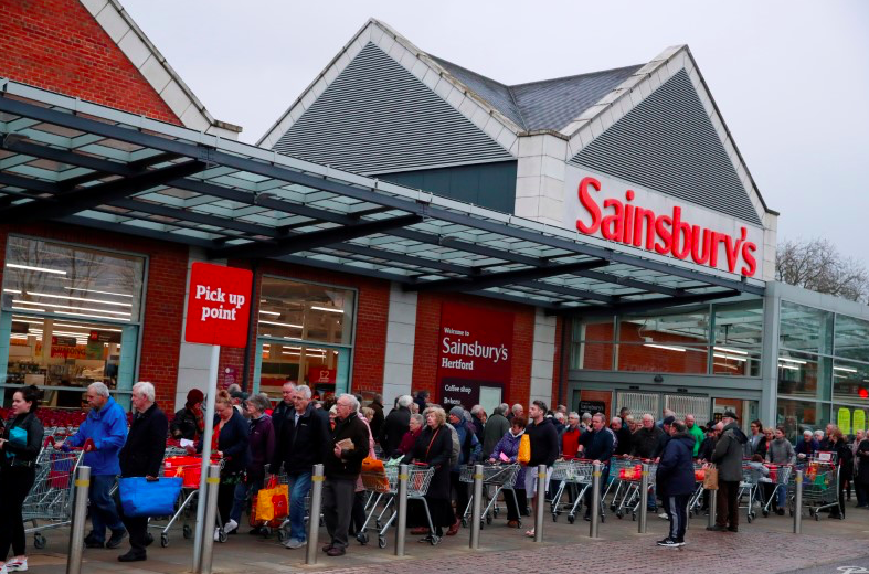 People queue to shop at Sainsbury's supermarket where the store had announced that the first hour of opening would be for elderly and vulnerable customers. (PA)