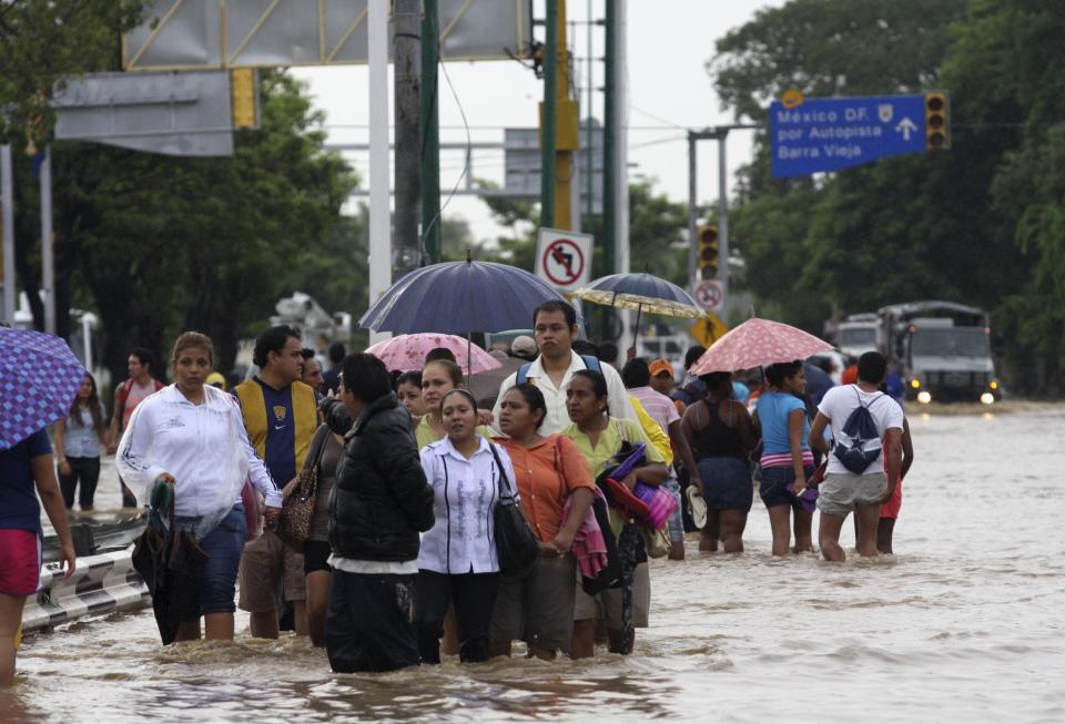 People walk through flooded streets in Acapulco September 17, 2013. Stranded tourists salvaged belongings from submerged cars in the Mexican beach resort of Acapulco which had become a floodplain on Tuesday after some of the worst storm damage in decades killed more than 50 people across the country. A three day downpour cut off several roads in Acapulco, wrecking cars and restricting the delivery of supplies to the Pacific port city of 750,000 people where the tourist trade has suffered in recent years from a surge in drug gang violence. REUTERS/Jacobo Garcia