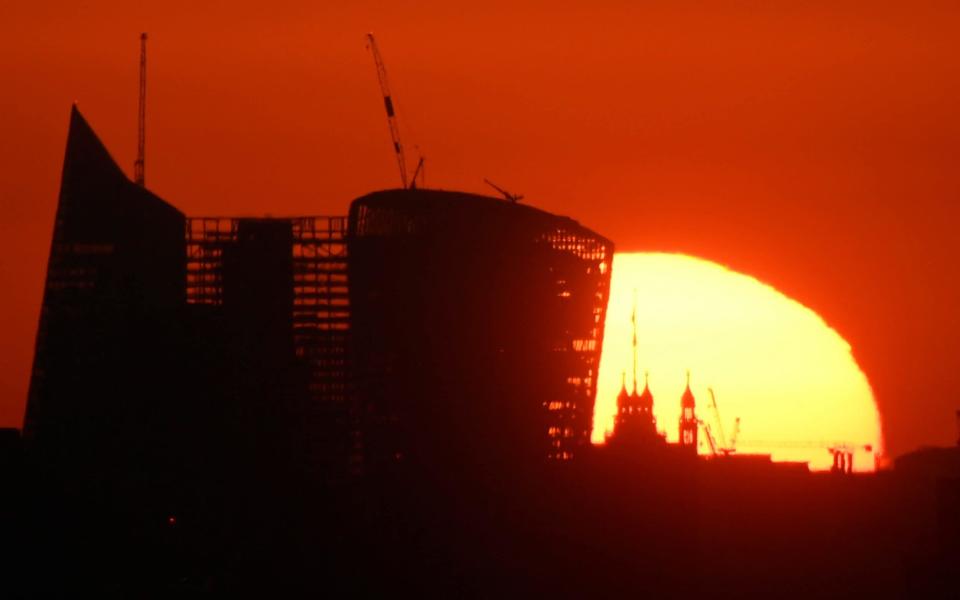 The sun rises behind skyscrapers in the City of London as a new heatwave begins - Toby Melville /Rueters