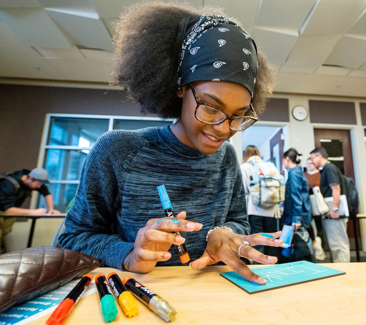 KaiJay Jiles, a theater administration major, writes a positive message on a tile for a loved one during the mental health resource fair at Concordia University Wisconsin on Sept. 20.