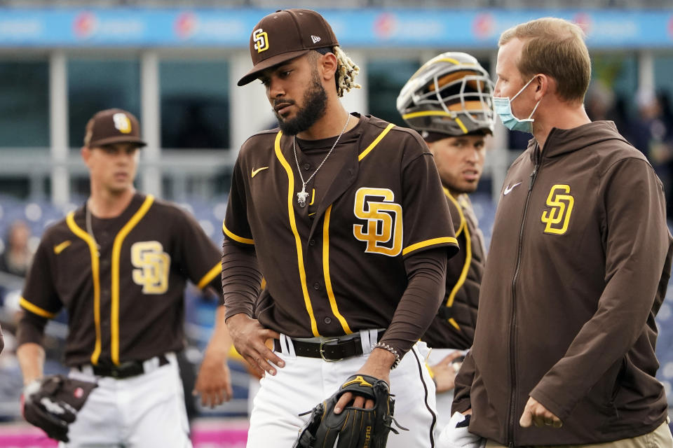 San Diego Padres shortstop Fernando Tatis Jr., center, leaves the field following an injury in the third inning of a spring training baseball game against the Cincinnati Reds Tuesday, March 23, 2021, in Peoria, Ariz. (AP Photo/Sue Ogrocki)