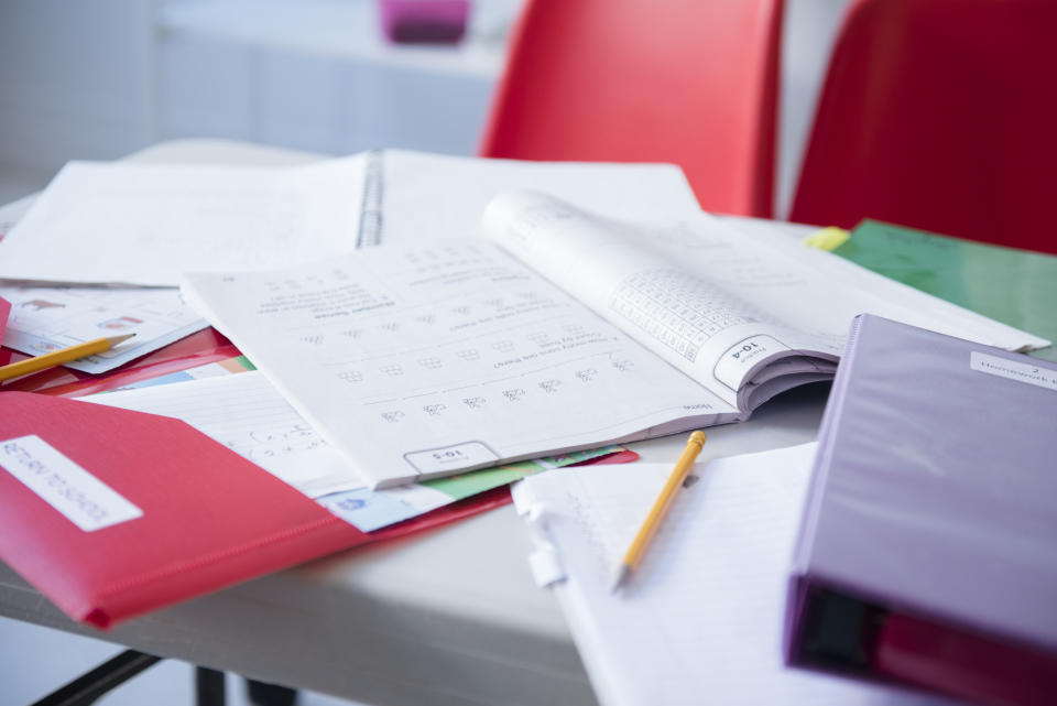 A cluttered desk with an open textbook, papers, and pencils, indicating study or work in progress