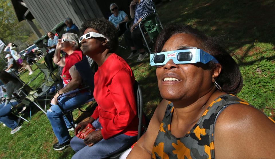 Arlene Roberts and others watch as the moon passes between the Earth and the sun Monday afternoon, April 8, 2024, at the Gateway Trail in Kings Mountain.