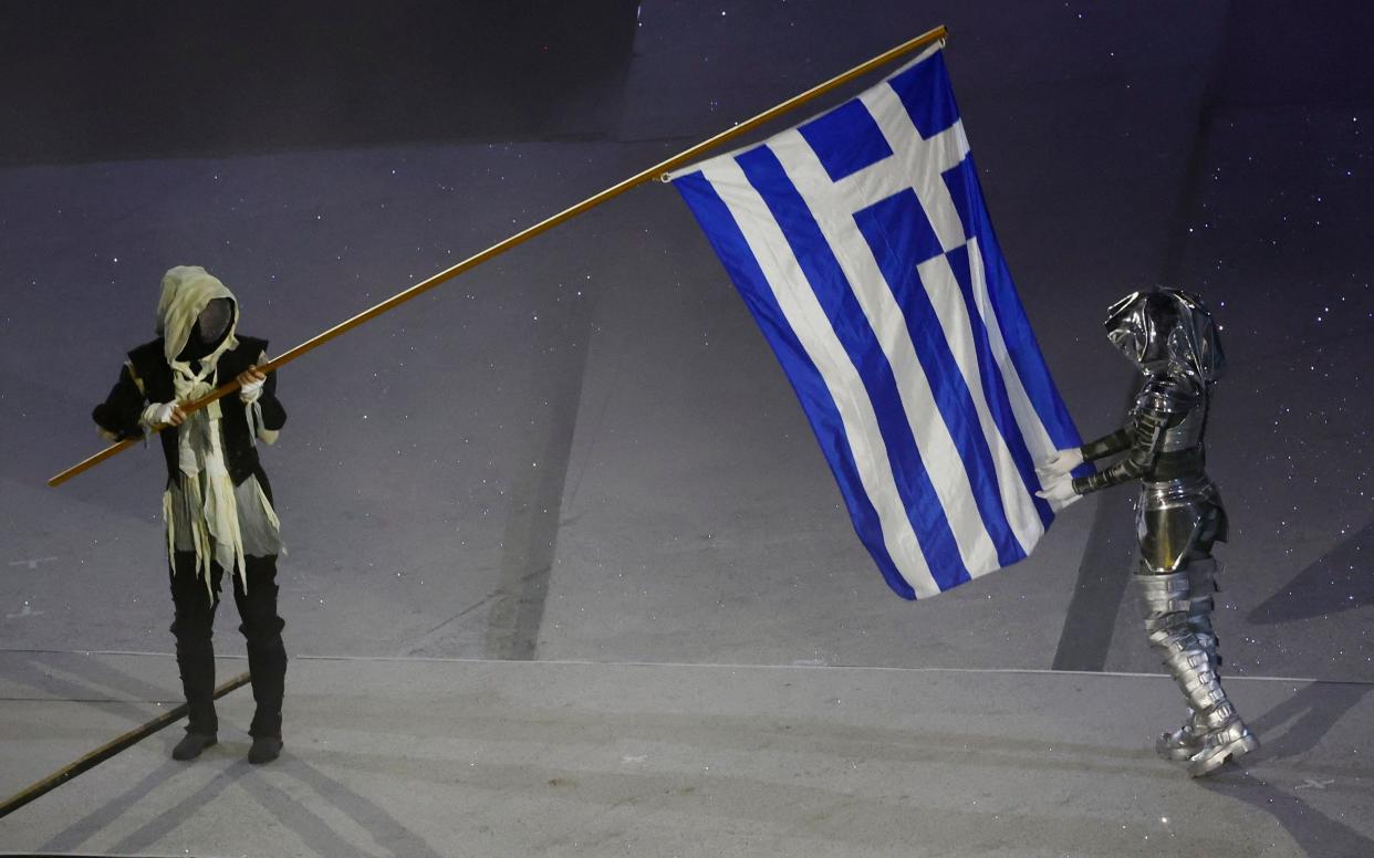 Performers carry the national flag of Greece.