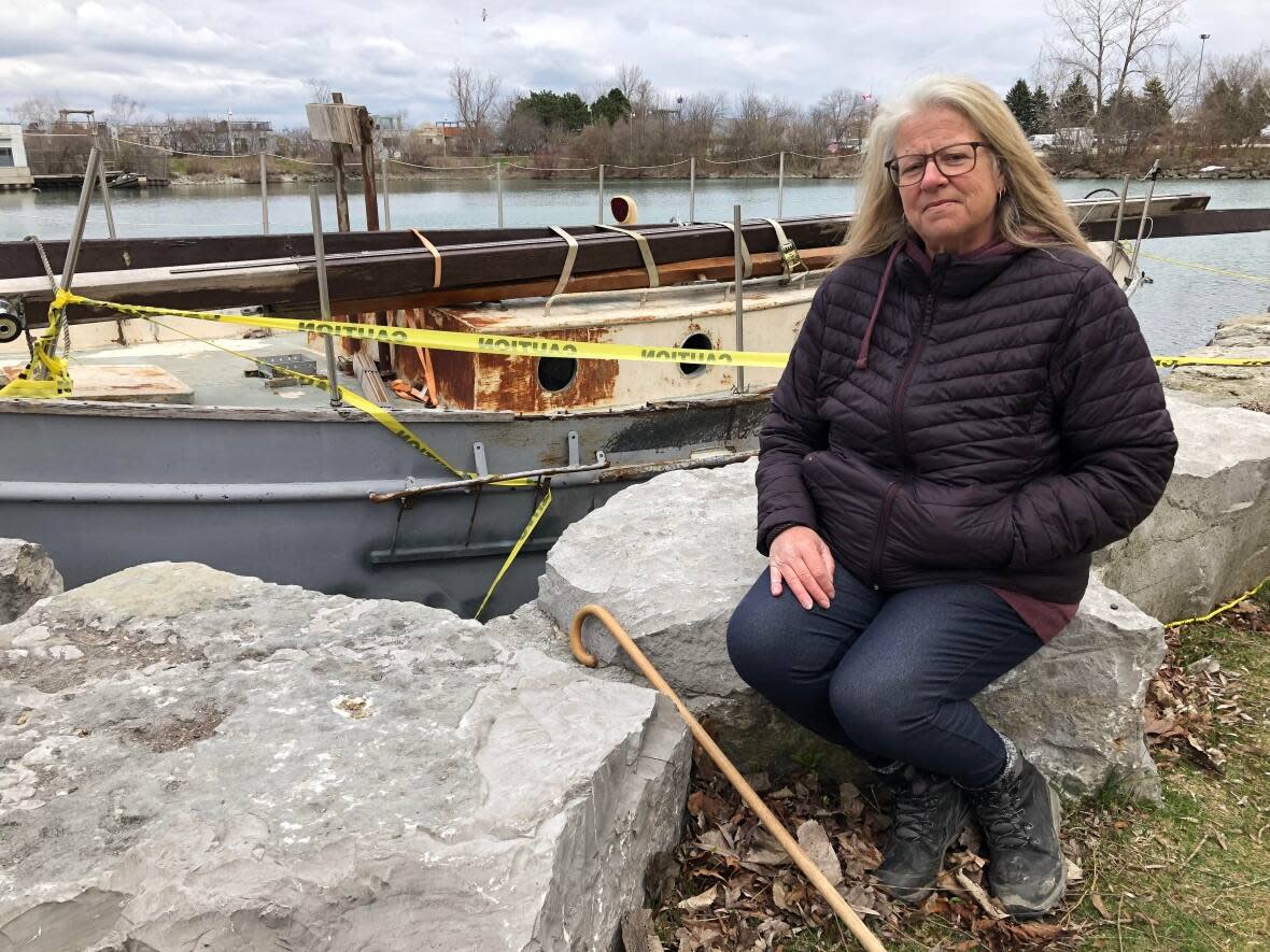 Cori Campbell calls the problem of wrecked boats in Bluffers Park 'heartbreaking.'  In the background is an abandoned boat that's been there for months awaiting removal by the federal government. Councillors want the city to be able to act unilaterally. (Sue Reid/CBC - image credit)