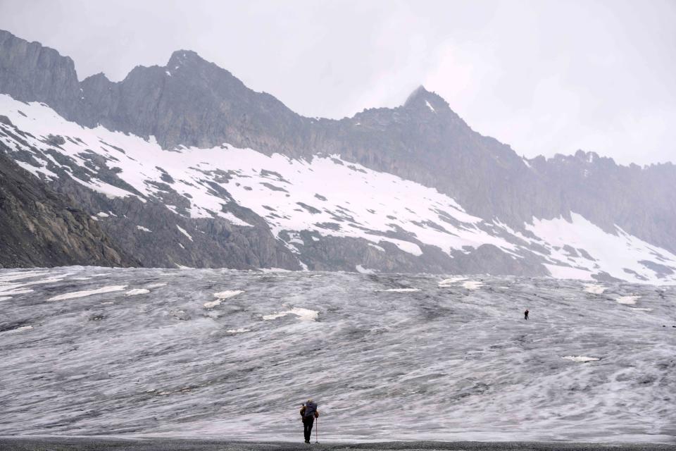 A cameraman walks up to the Rhone Glacier near Goms, Switzerland, Friday, June 16, 2023. (AP Photo/Matthias Schrader)