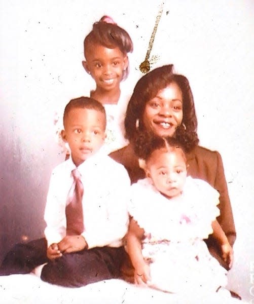 a family of a mom and three young kids pose for a photo, all dressed up