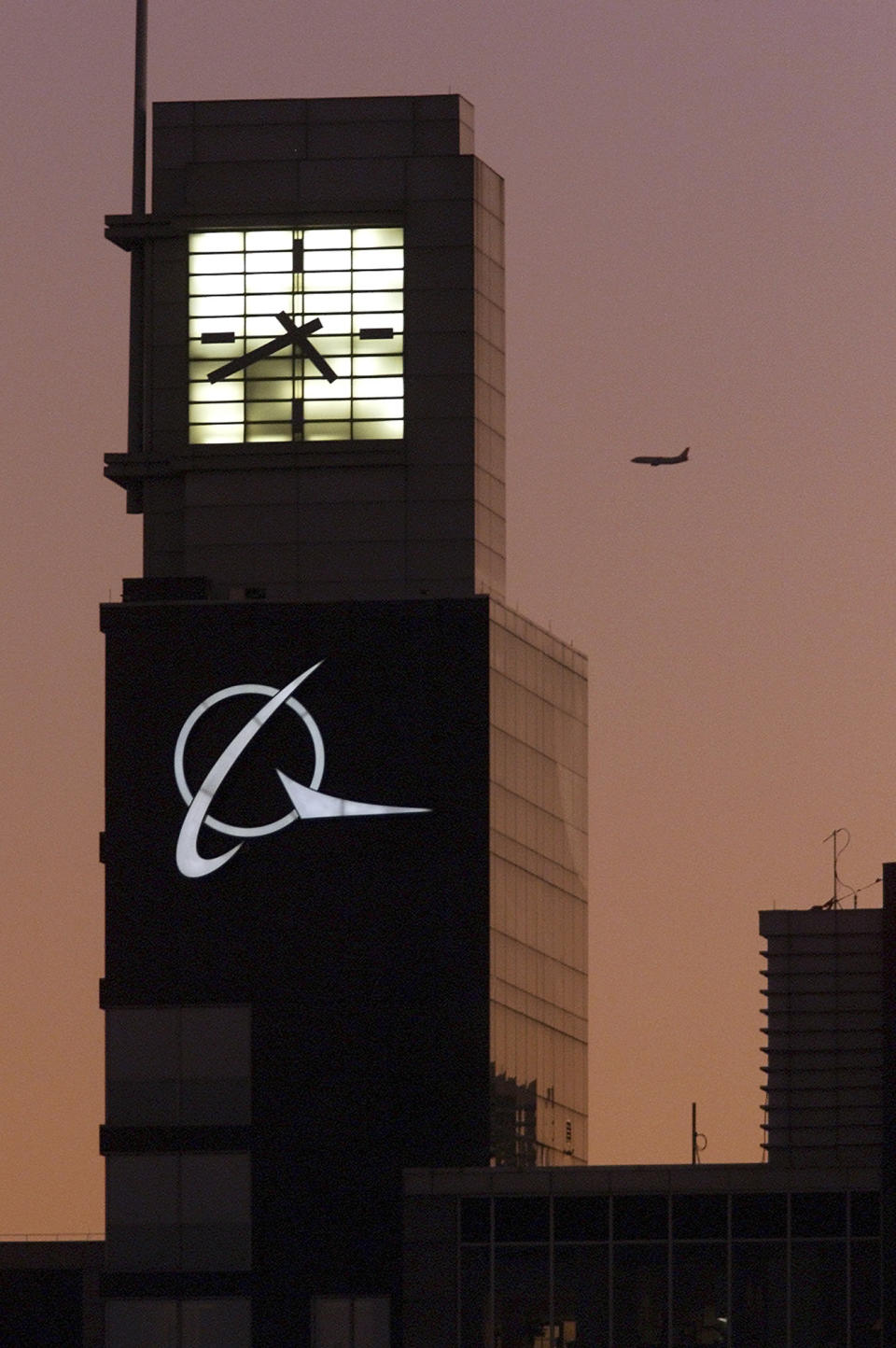 FILE - An airplane flies past the Boeing logo on the company's headquarters in Chicago, on Thursday, Dec. 20, 2001. Boeing Co., a leading defense contractor and one of the world's two dominant manufacturers of airline planes, is expected to move its headquarters from Chicago to the Washington, D.C., area, according to two people familiar with the matter. The decision could be announced as soon as later Thursday, May 5, 2022, according to one of the people. (AP Photo/Ted S. Warren, File)