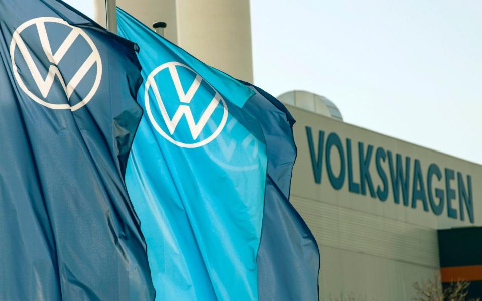 FILE - In this file photo dated Thursday, April 23, 2020, flags wave in front of a factory building during the production restart of the plant of the German manufacturer Volkswagen AG (VW) in Zwickau, Germany. Carmaker Volkswagen reports Thursday July 30, 2020, an after-tax loss of 1.54 billion euros (dollars 1.81 billion) in the second quarter as the pandemic shut down auto plants and closed dealerships. (AP Photo/Jens Meyer, FILE) -  Jens Meyer/AP