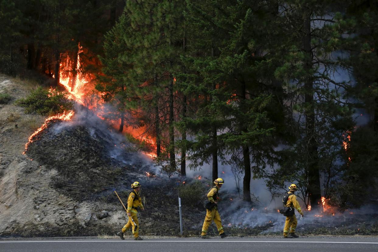 Firefighters monitor flames above State Highway 299 while battling the Carr Fire: Getty